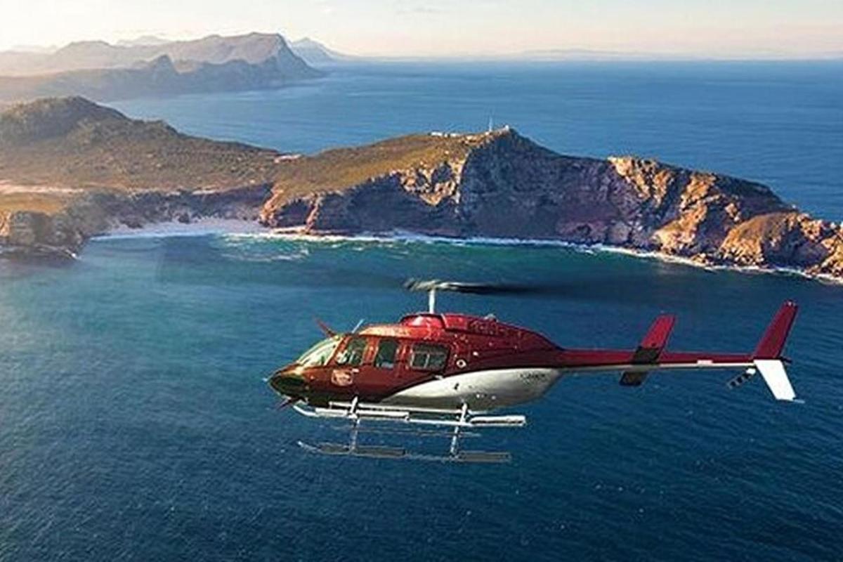 a red and white helicopter flying over the ocean