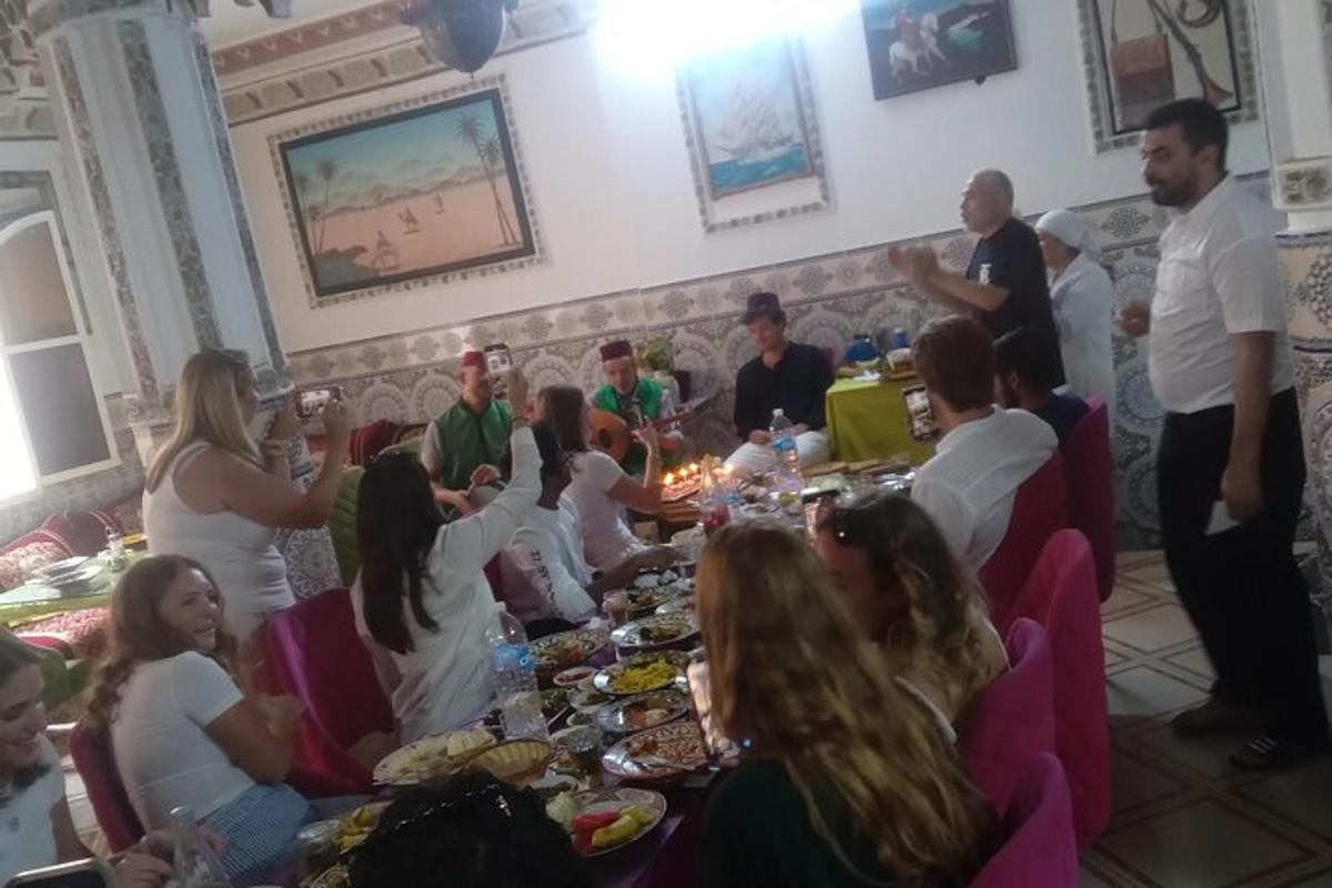 grupp inimesi, kes istuvad laua ümber ja söövad toitu