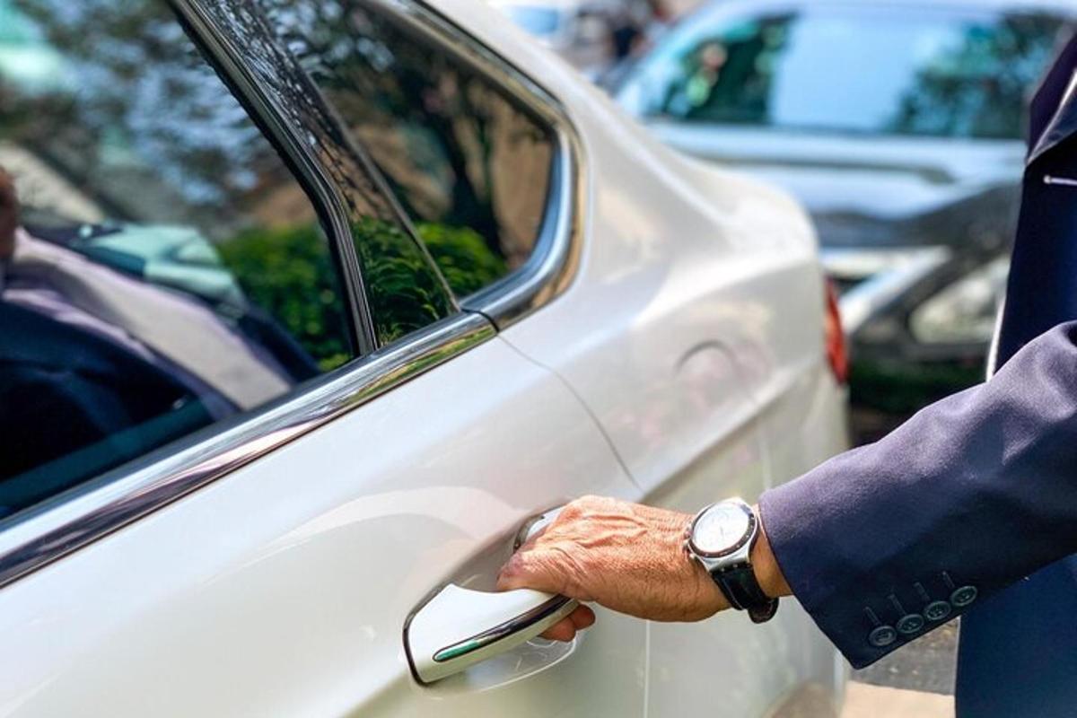 un uomo che tiene la portiera di un'auto bianca