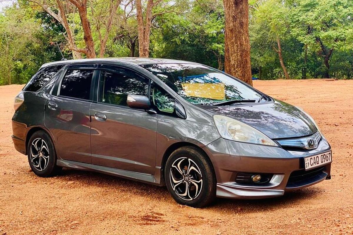 một chiếc xe nhỏ màu bạc đỗ trên một cánh đồng đất