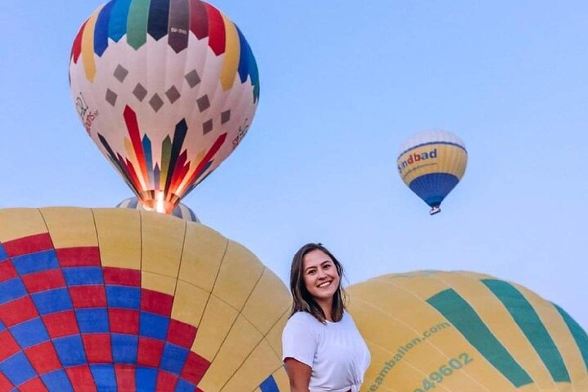 a woman standing next to three hot air balloons