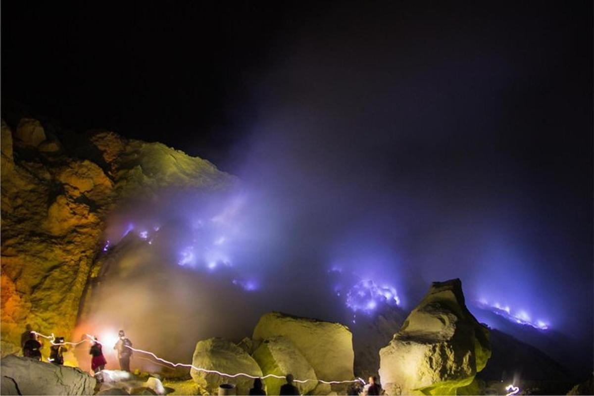 un gruppo di persone in piedi davanti a una cascata di notte