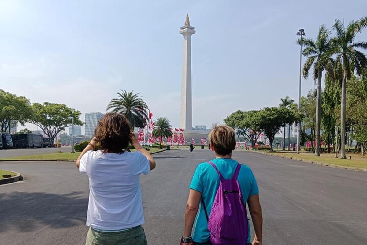 Două persoane mergând pe o stradă privind un monument