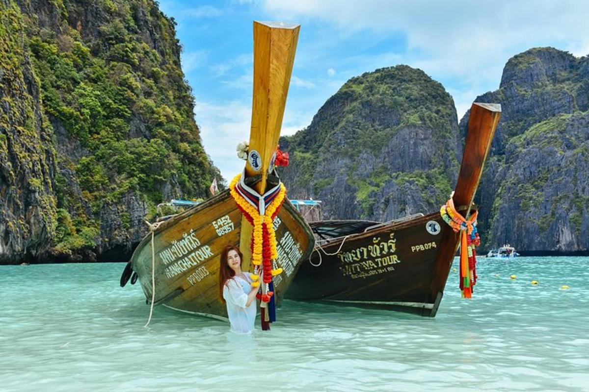 a woman standing in the water next to two boats