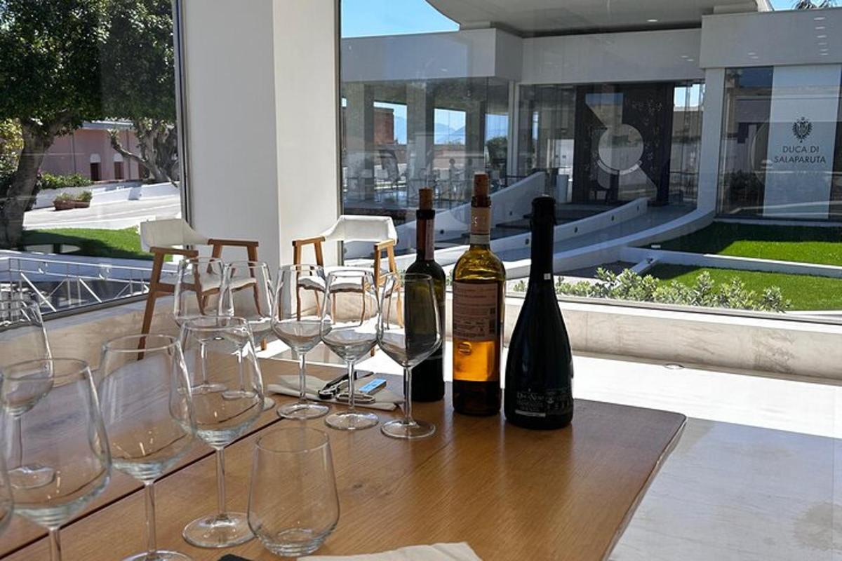 tre bottiglie di vino appoggiate su un tavolo con bicchieri da vino