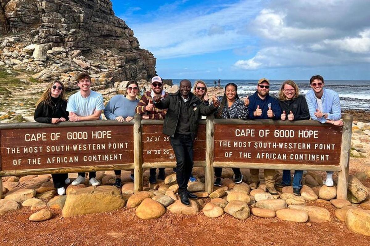 um grupo de pessoas em pé atrás de uma placa na praia