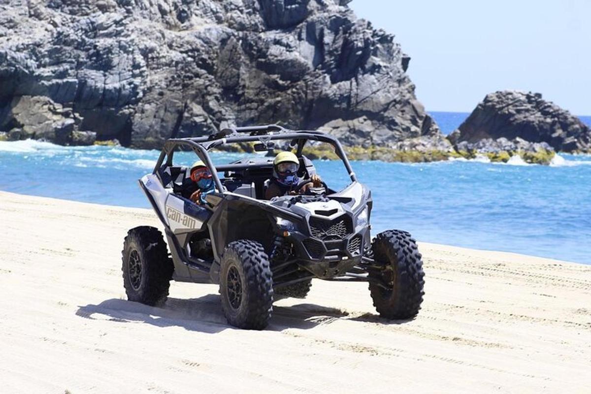 twee mensen rijden in een vierwieler op het strand