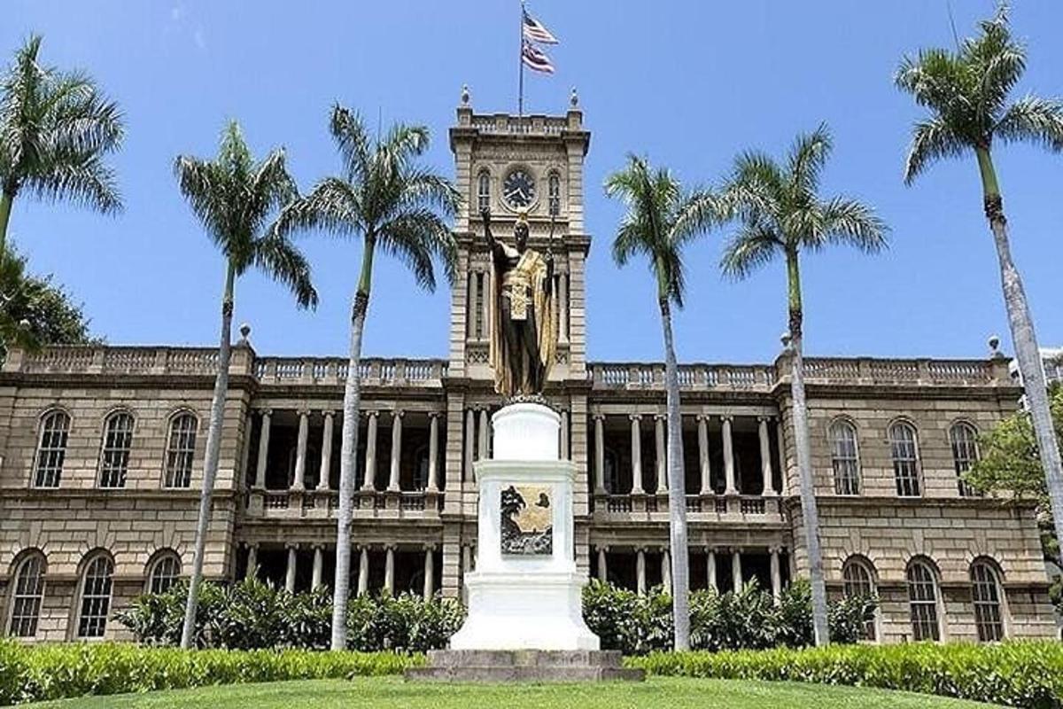 Un edificio con una torre de reloj con una estatua delante.