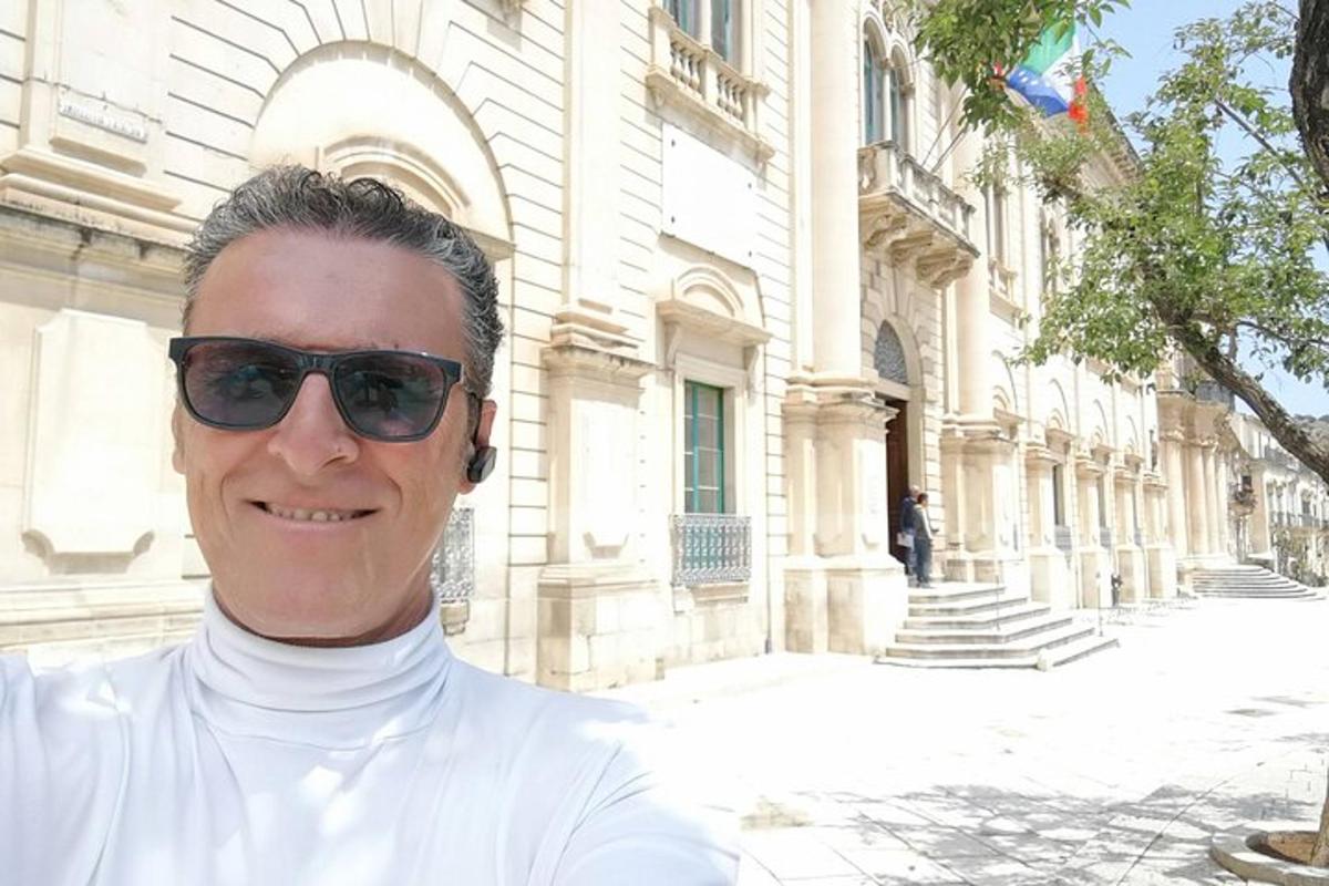 un bărbat purtând ochelari de soare stând în fața unei clădiri