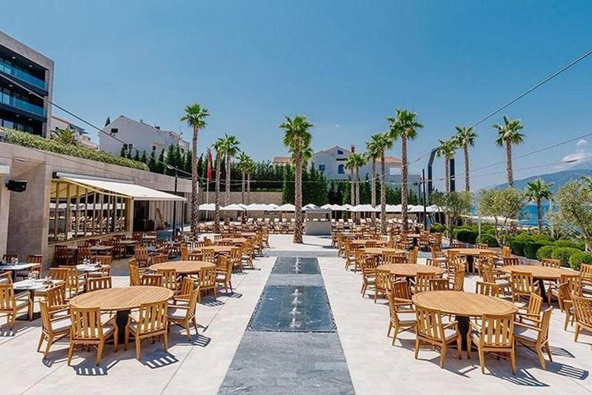 eine leere Terrasse mit Tischen und Stühlen und Palmen
