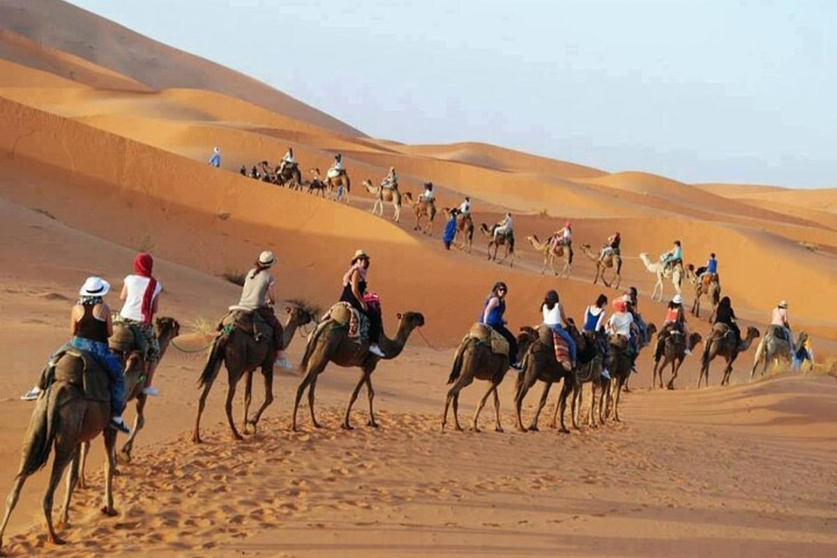 un gruppo di persone a cavallo di cammelli nel deserto