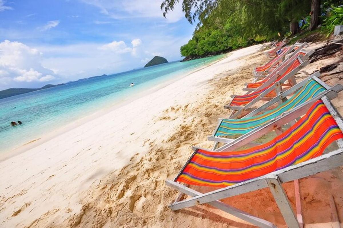 eine Reihe von Liegestühlen an einem Strand