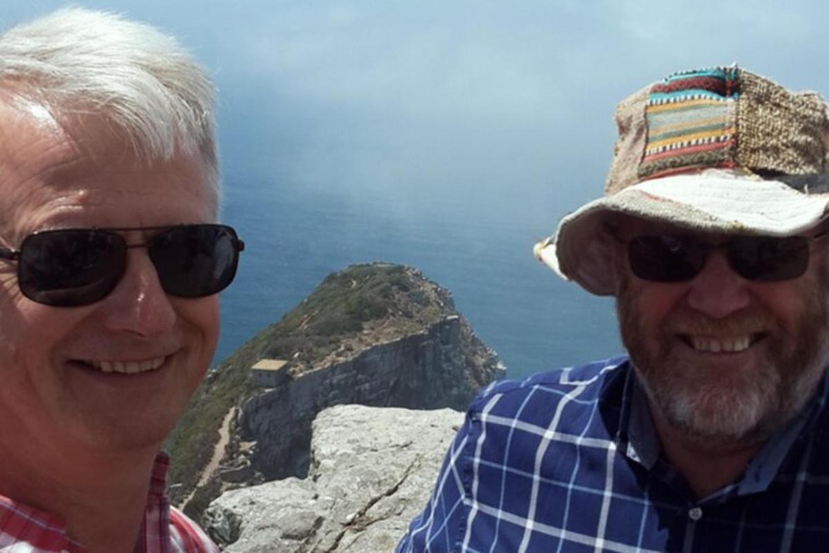 Dos hombres con gafas de sol y sombrero en la cima de una montaña