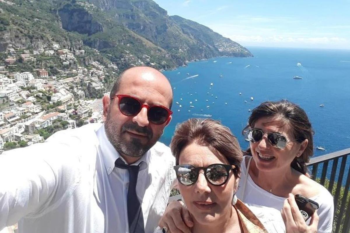 un grup de tres persones dretes en un balcó amb l'oceà