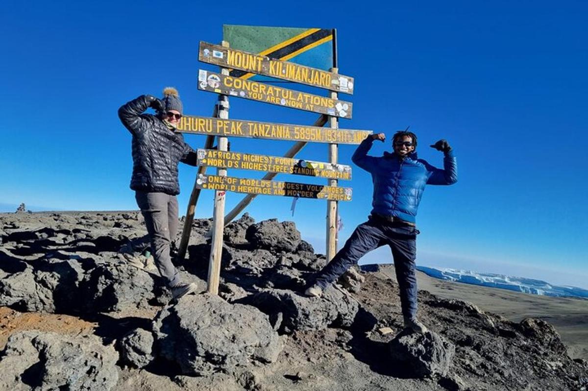 dua lelaki berdiri di sebelah papan tanda di puncak gunung