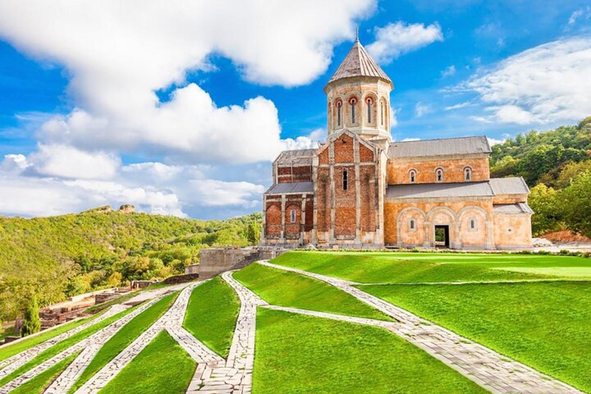 Stará cihlová budova s věží na zelené louce