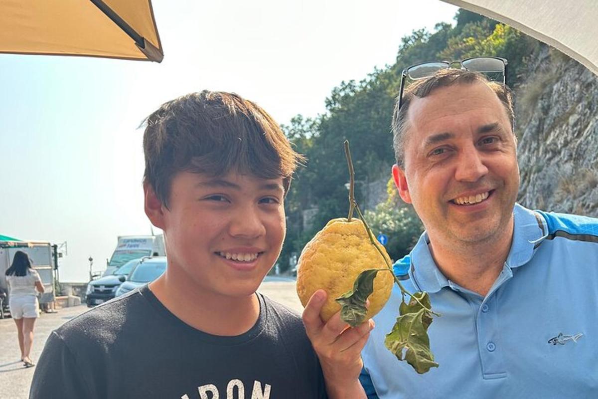 a man standing next to a young boy holding a sandwich