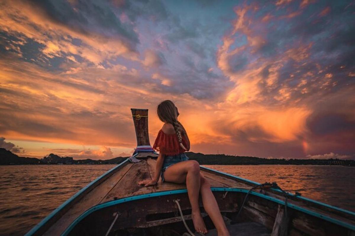 una donna seduta su una barca in acqua al tramonto