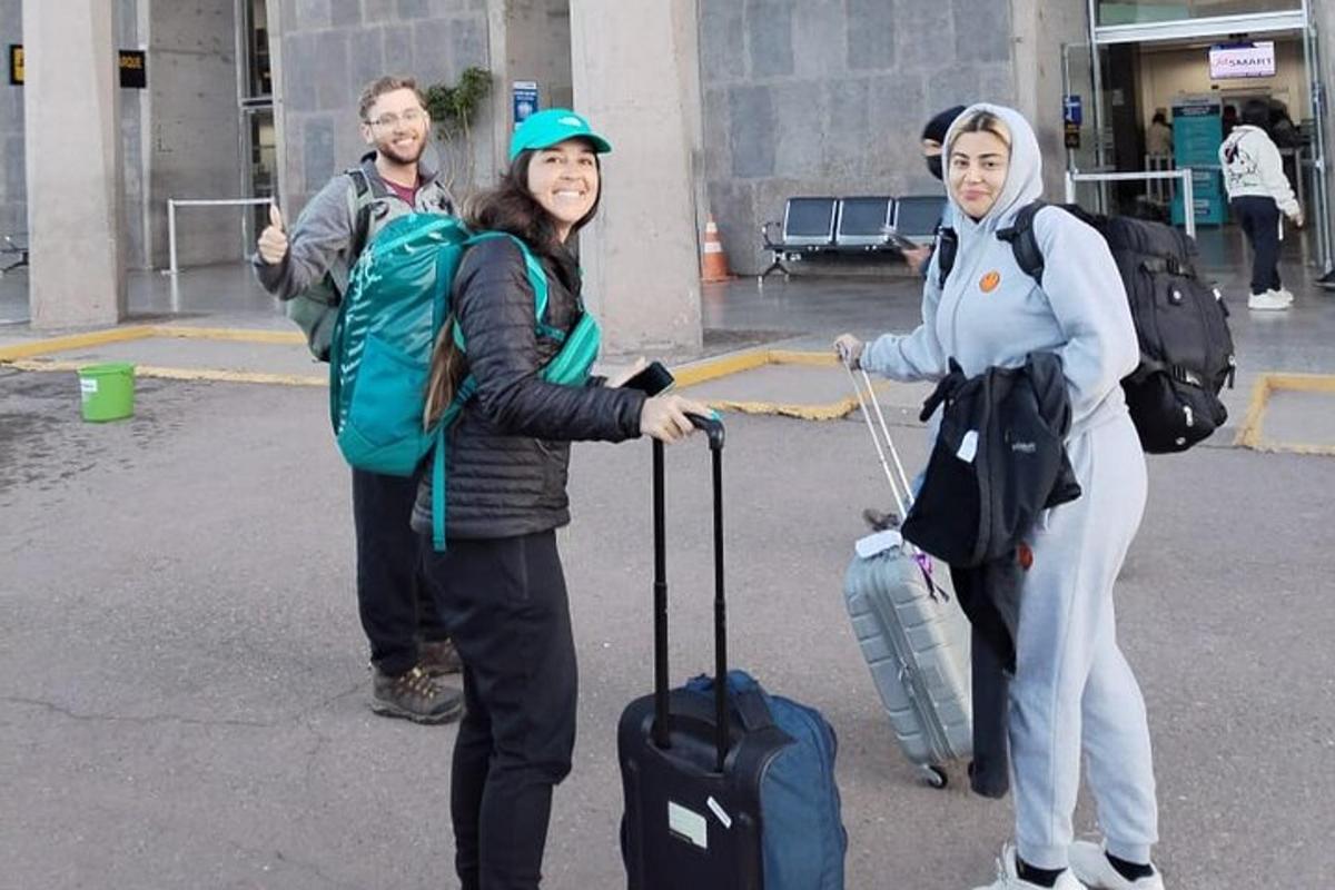 Un grupo de personas de pie con equipaje en un aeropuerto.