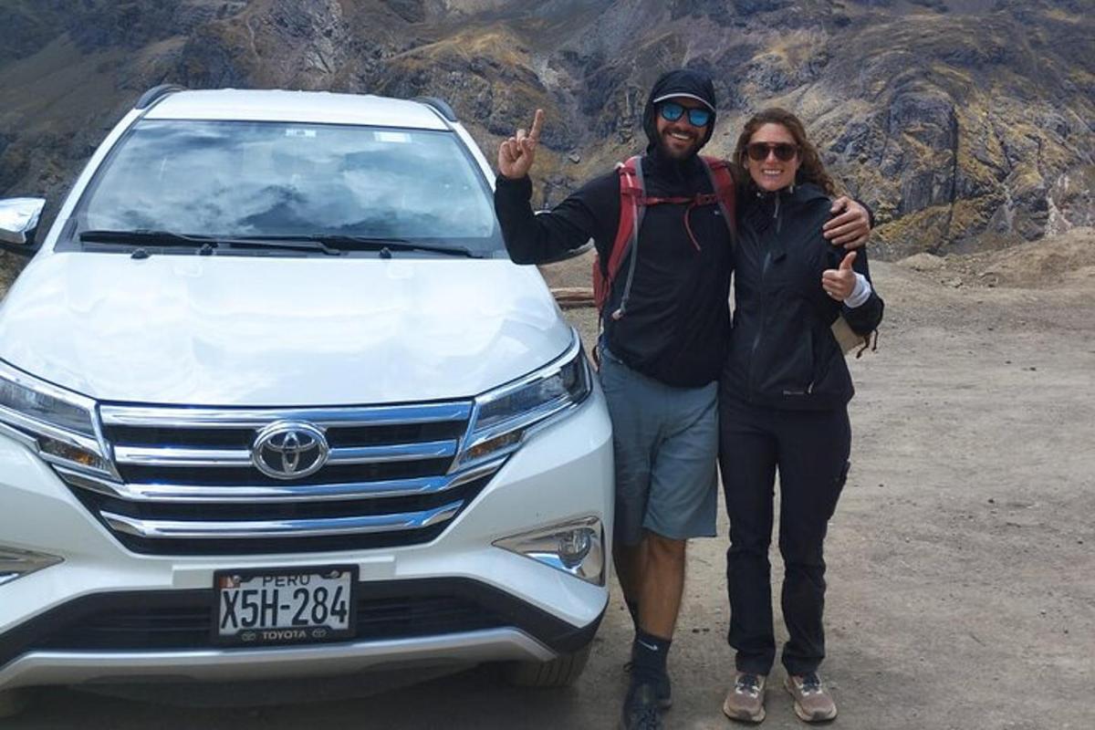 Un hombre y una mujer de pie junto a una camioneta blanca.