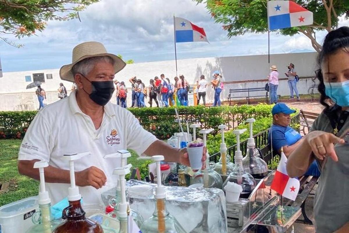 ein Mann mit Gesichtsmaske an einem mit Flaschen gefüllten Tisch
