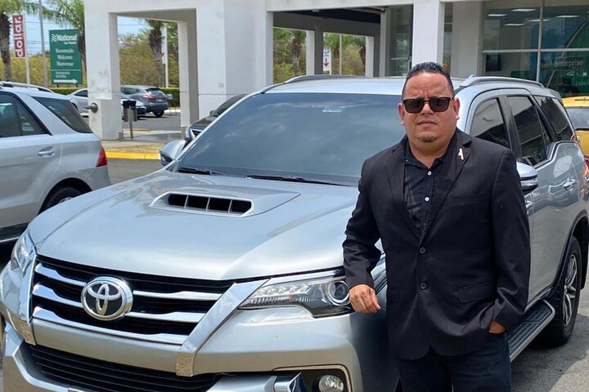 um homem parado na frente de um carro prateado