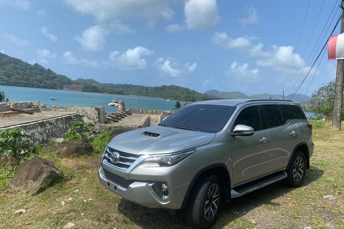 isang silver SUV ang nakaparada sa isang burol sa tabi ng isang lawa