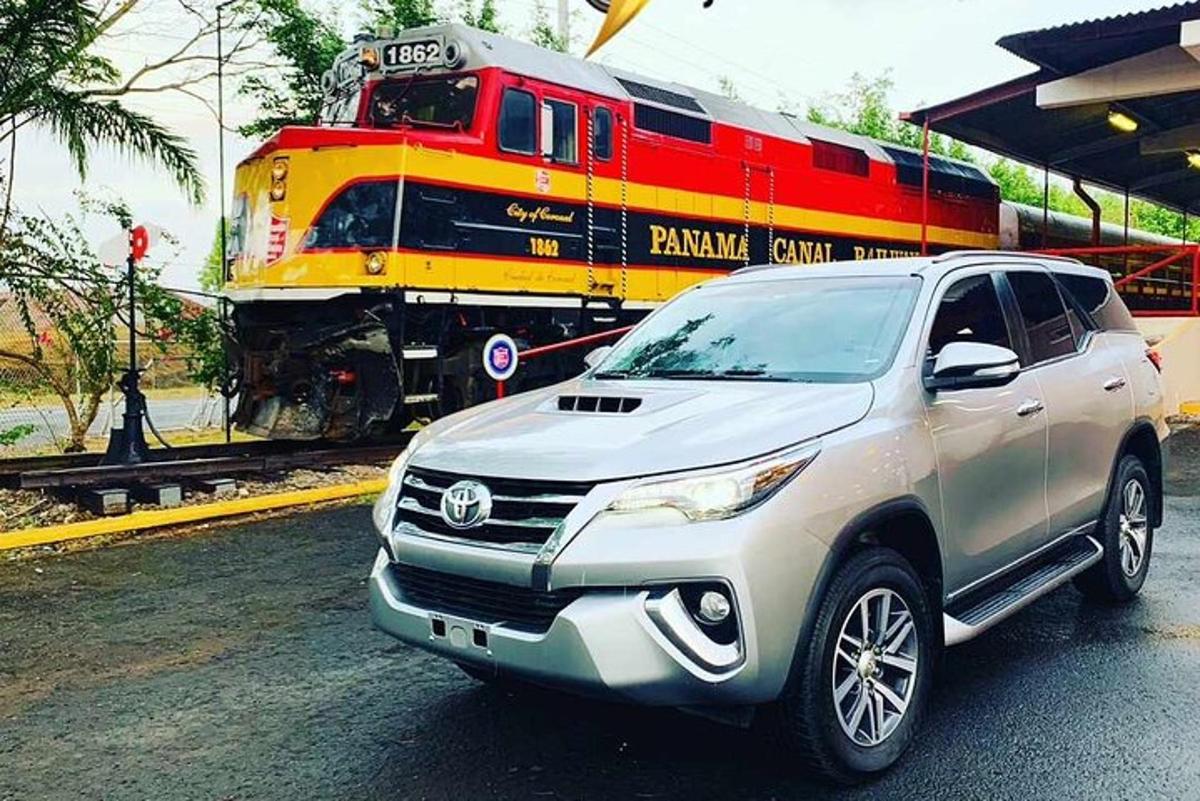 um SUV prateado estacionado na frente de um trem