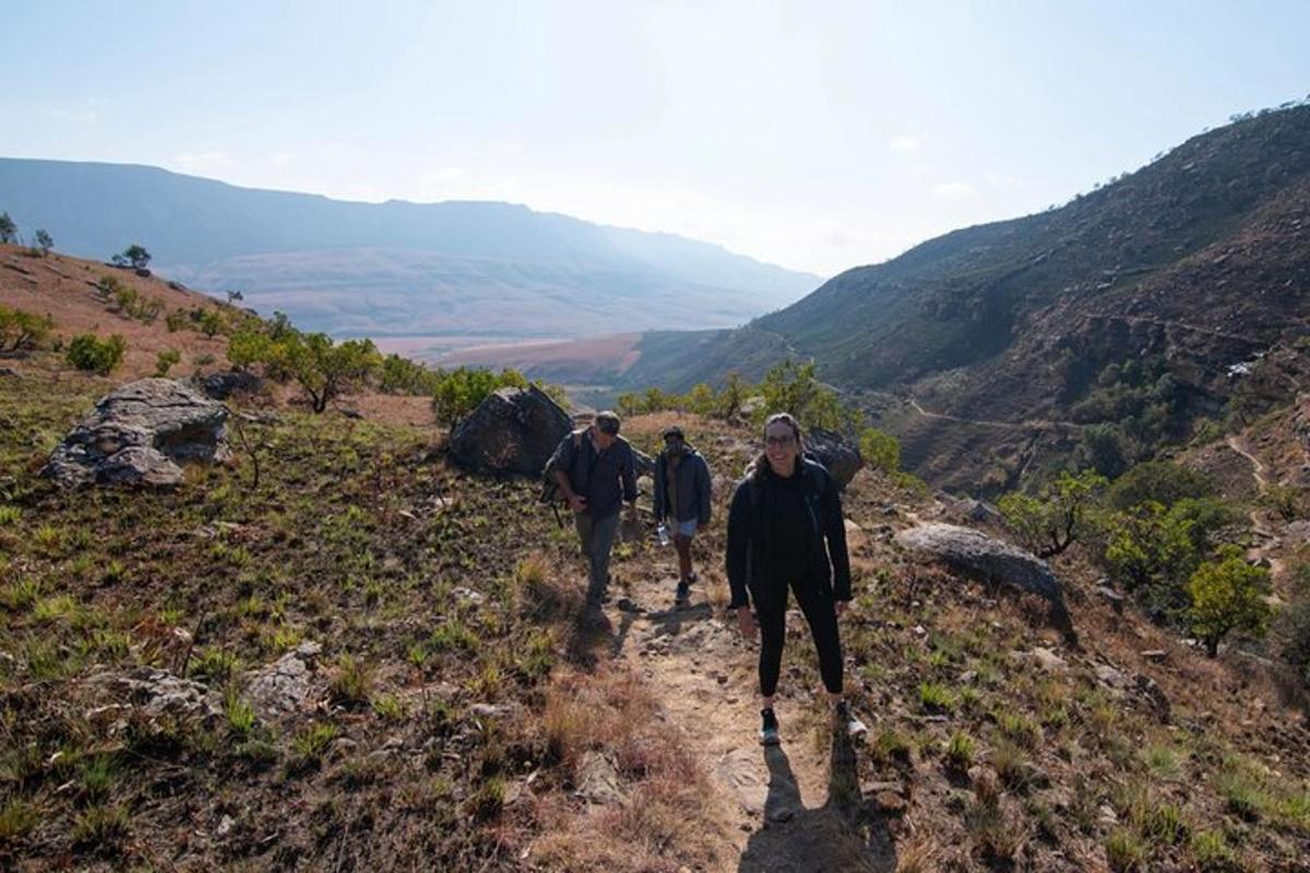 three people walking down a trail on a mountain