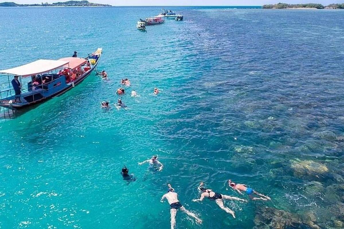 a group of people swimming in the water next to a boat