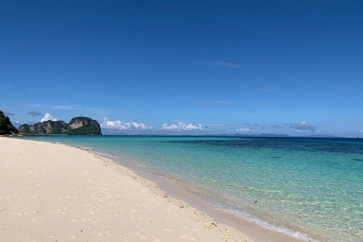 una spiaggia con acqua blu e rocce sullo sfondo