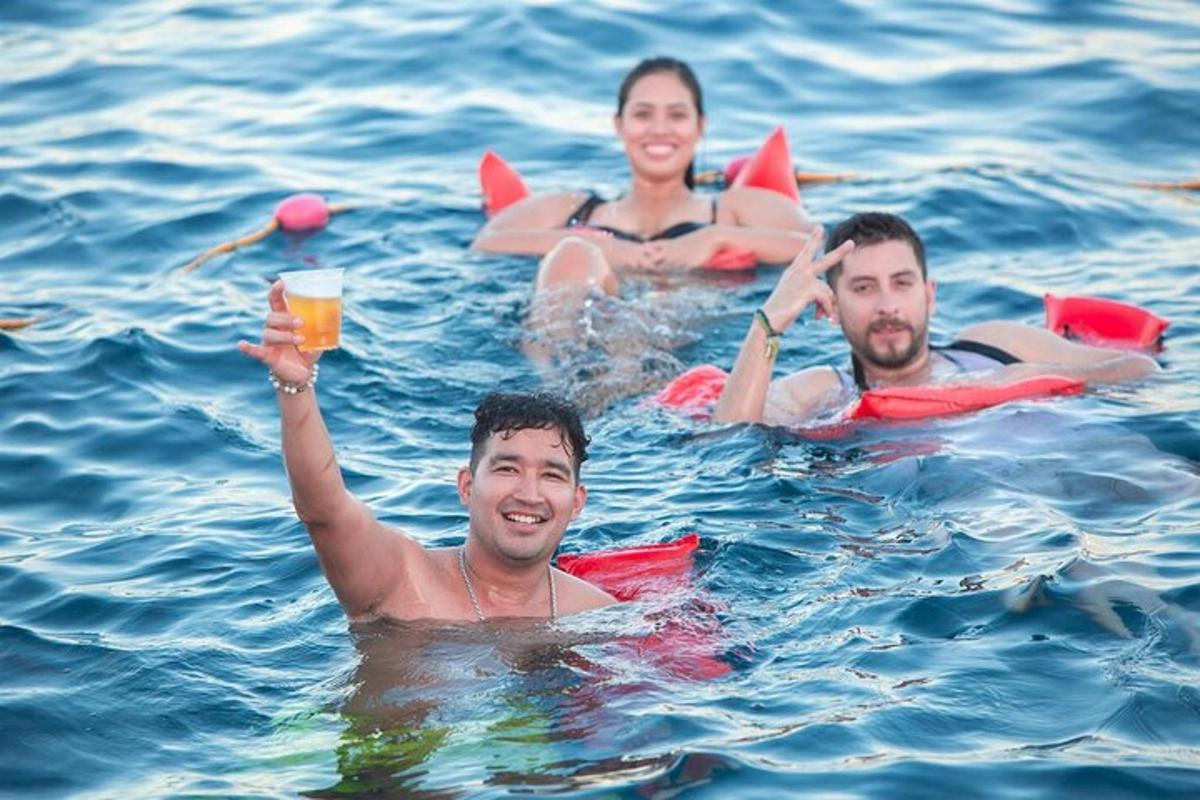 three people in the water with a glass of beer