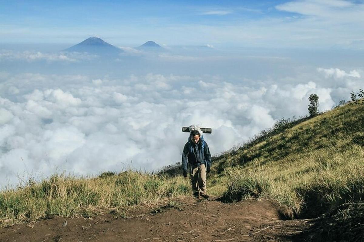 một người đàn ông đứng trên đỉnh đồi phía trên những đám mây