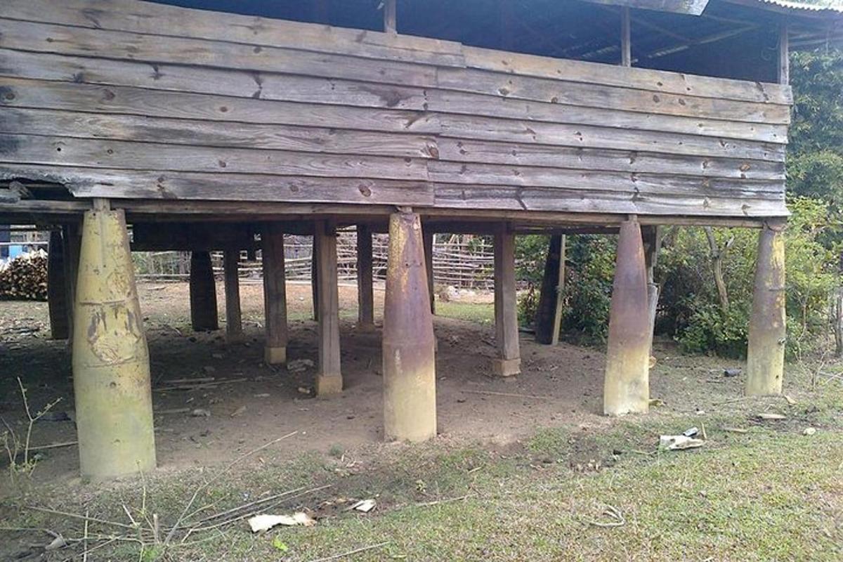 a wooden building with pillars in a field