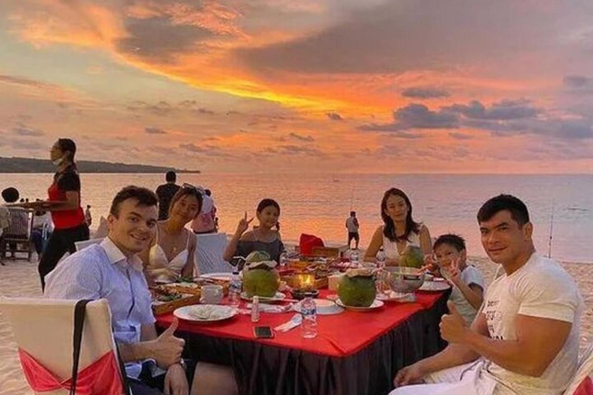 um grupo de pessoas comendo em uma mesa na praia