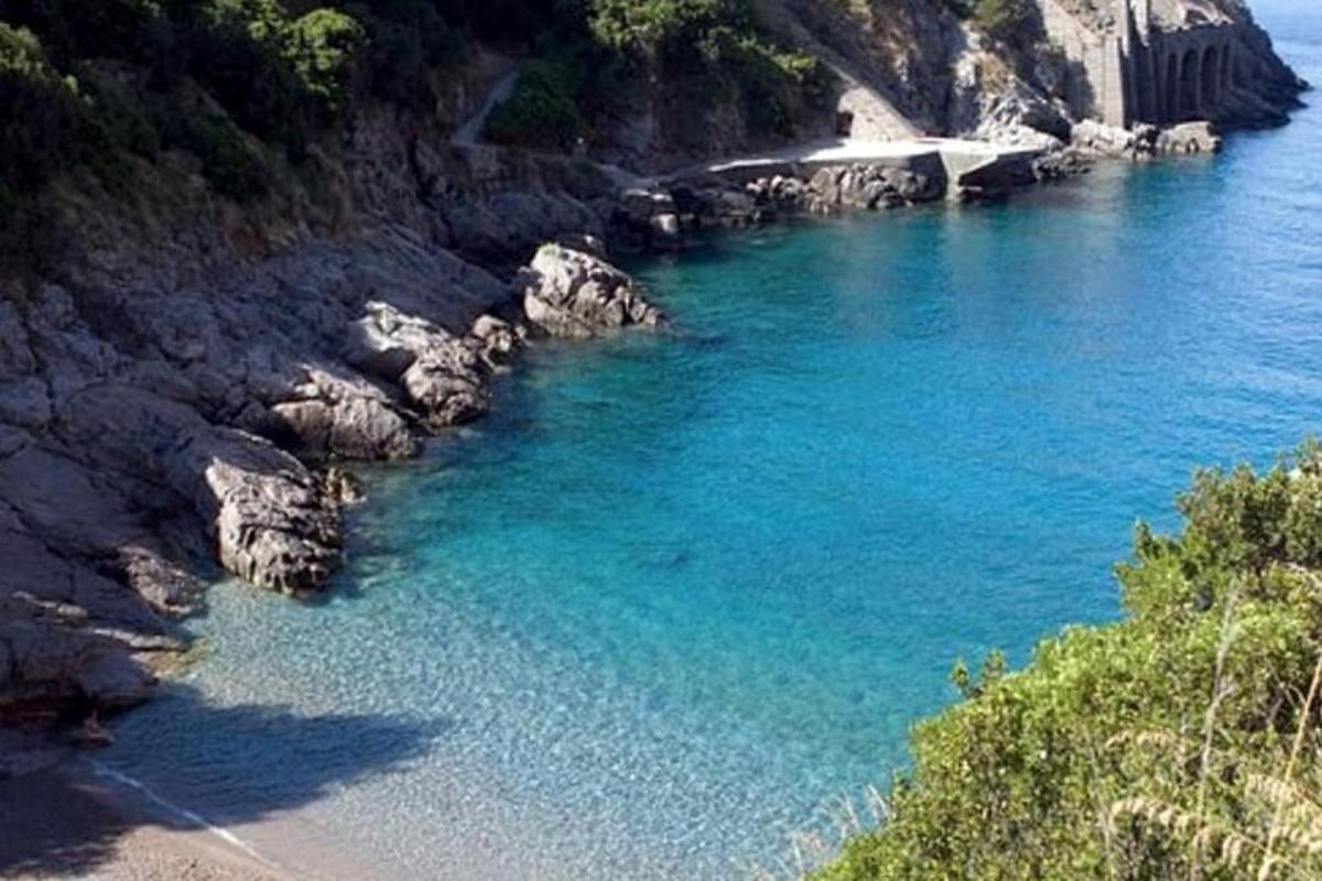 una spiaggia con acqua blu e rocce e un ponte