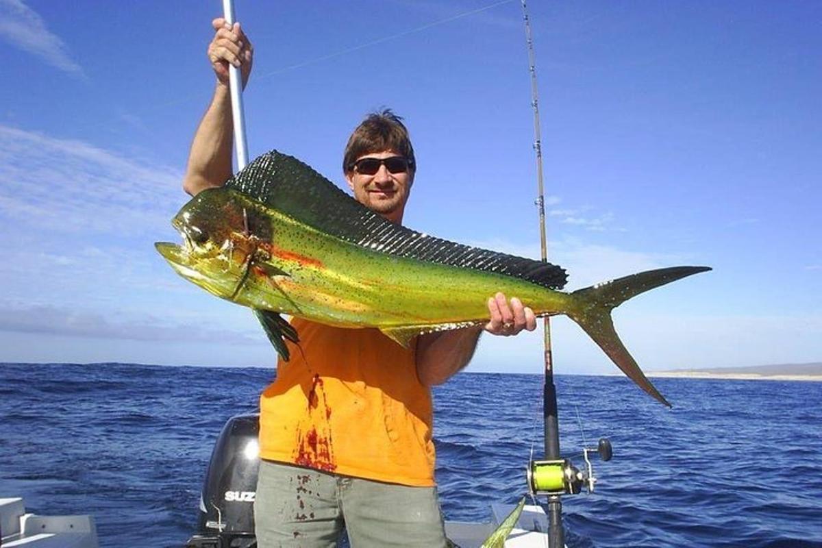 un uomo che tiene in mano un pesce su una barca