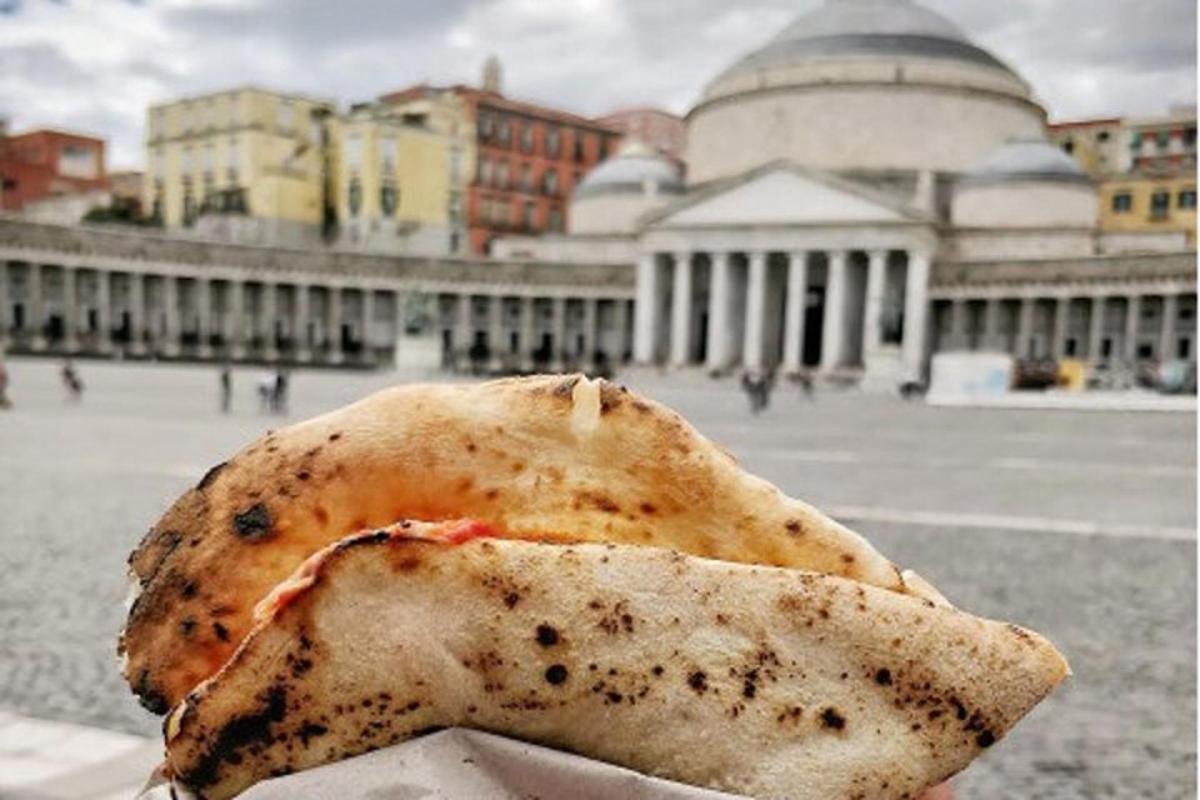 egy személy, aki egy szelet pizzát tart a kezében