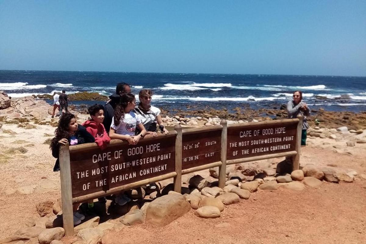 un gruppo di persone sedute su un cartello in spiaggia