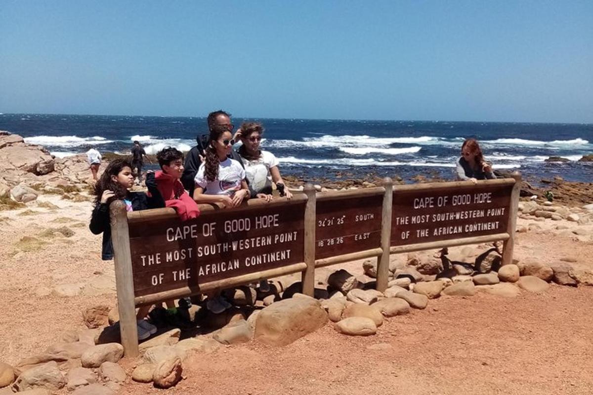 un gruppo di persone sedute su un cartello in spiaggia