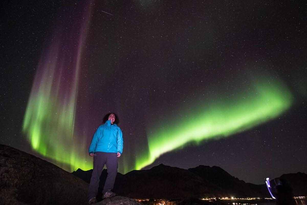 maður stendur undir norðurljósum á himninum