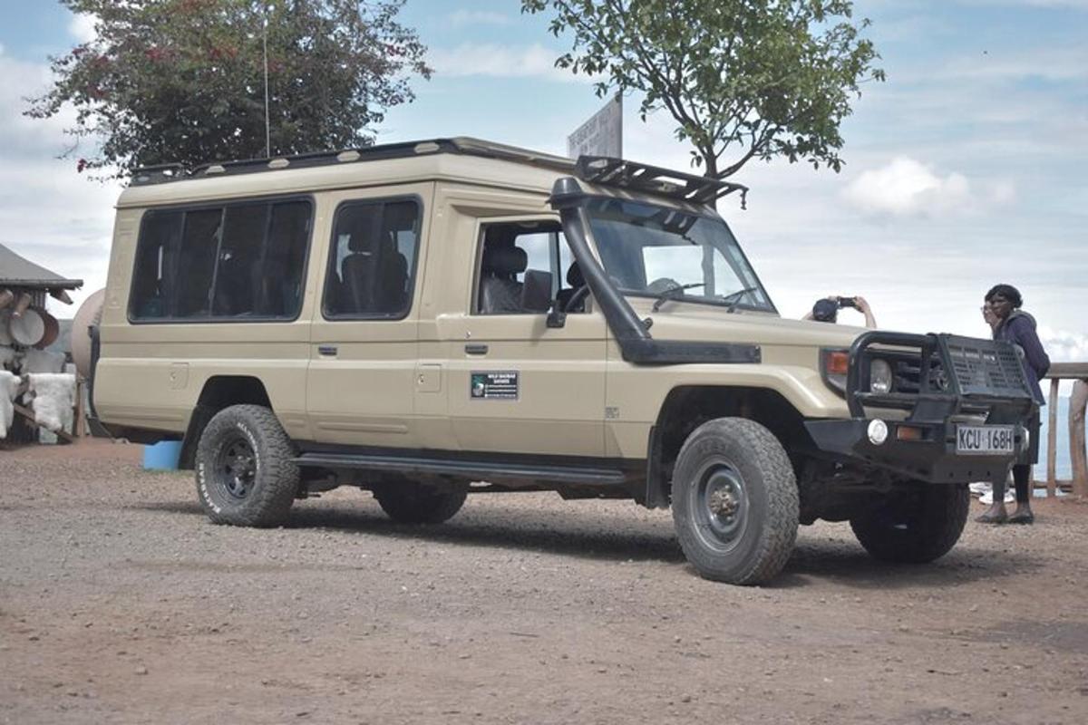 Un jeep color canela estacionado en un camino de tierra con gente parada alrededor.