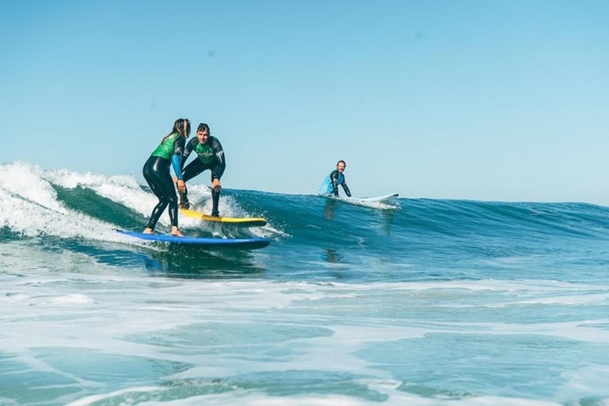 tři lidé jedou na vlně na surfových prknech v oceánu