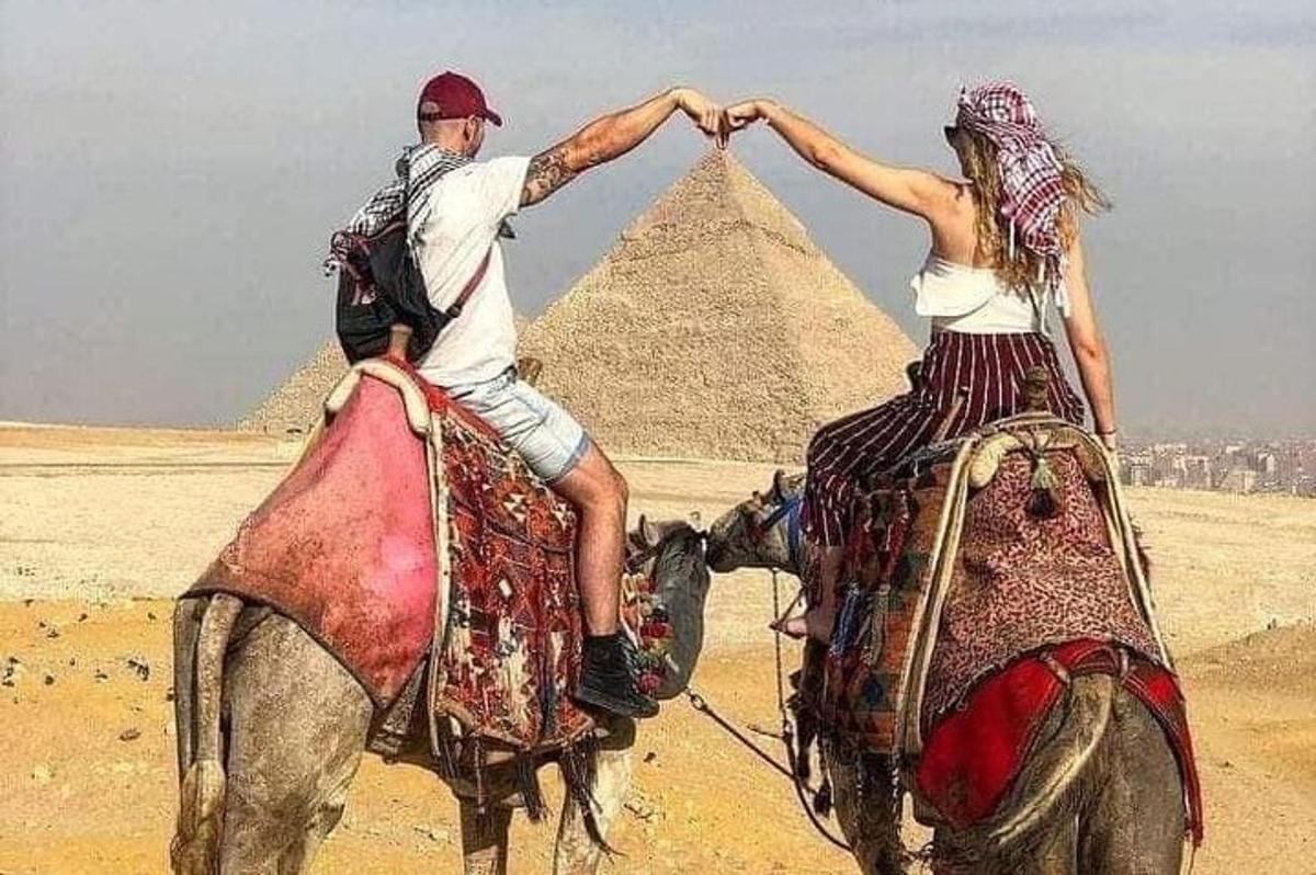 muž a žena jedoucí na koních před pyramidami
