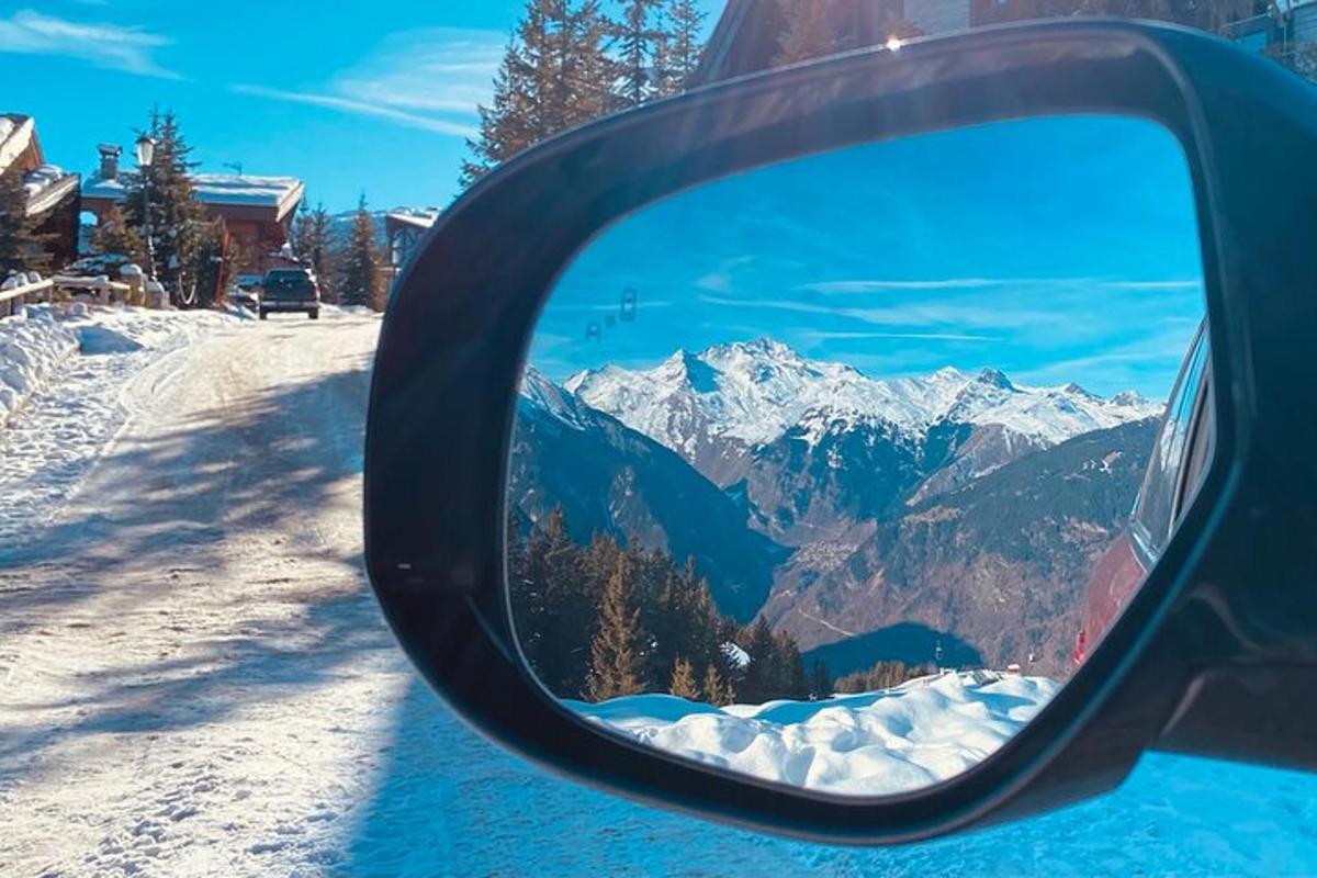 a side view mirror of a car with a view of mountains