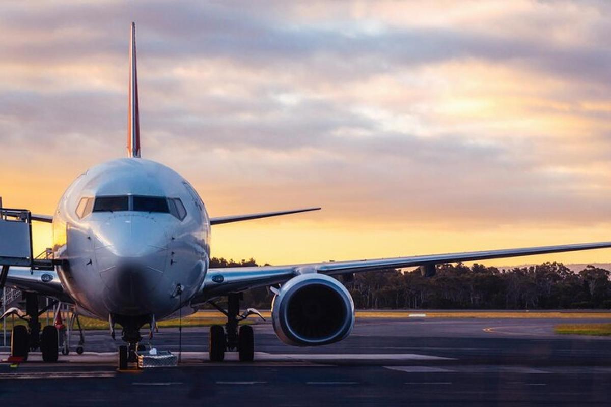 um avião está parado na pista ao pôr do sol