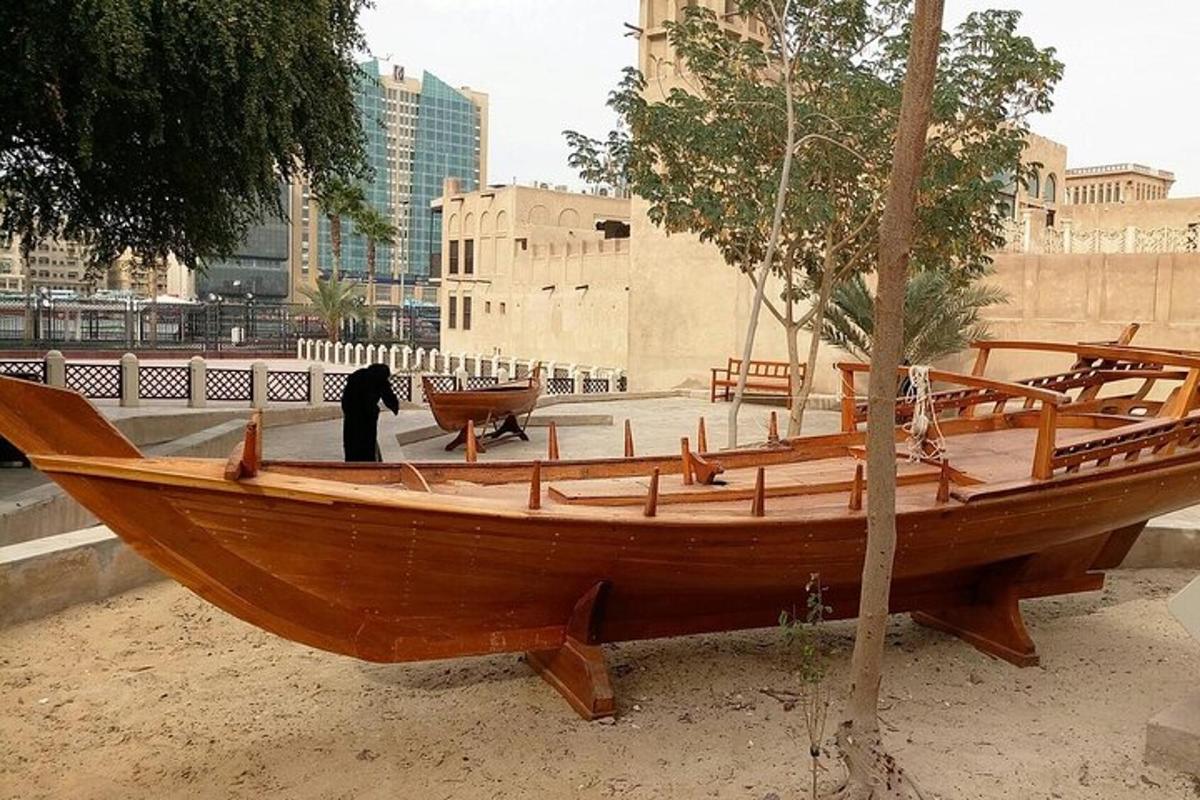 a wooden boat sitting on the ground next to a tree