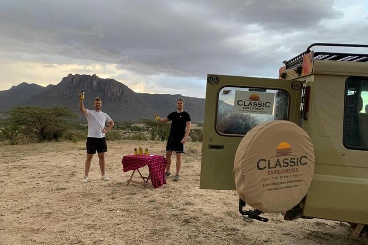dois homens em pé na frente de um trailer com uma mesa na frente
