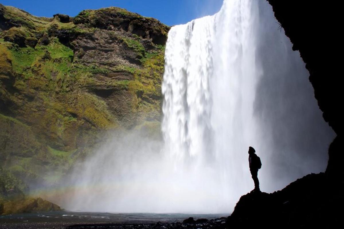 a man standing on a rock in front of a waterfall