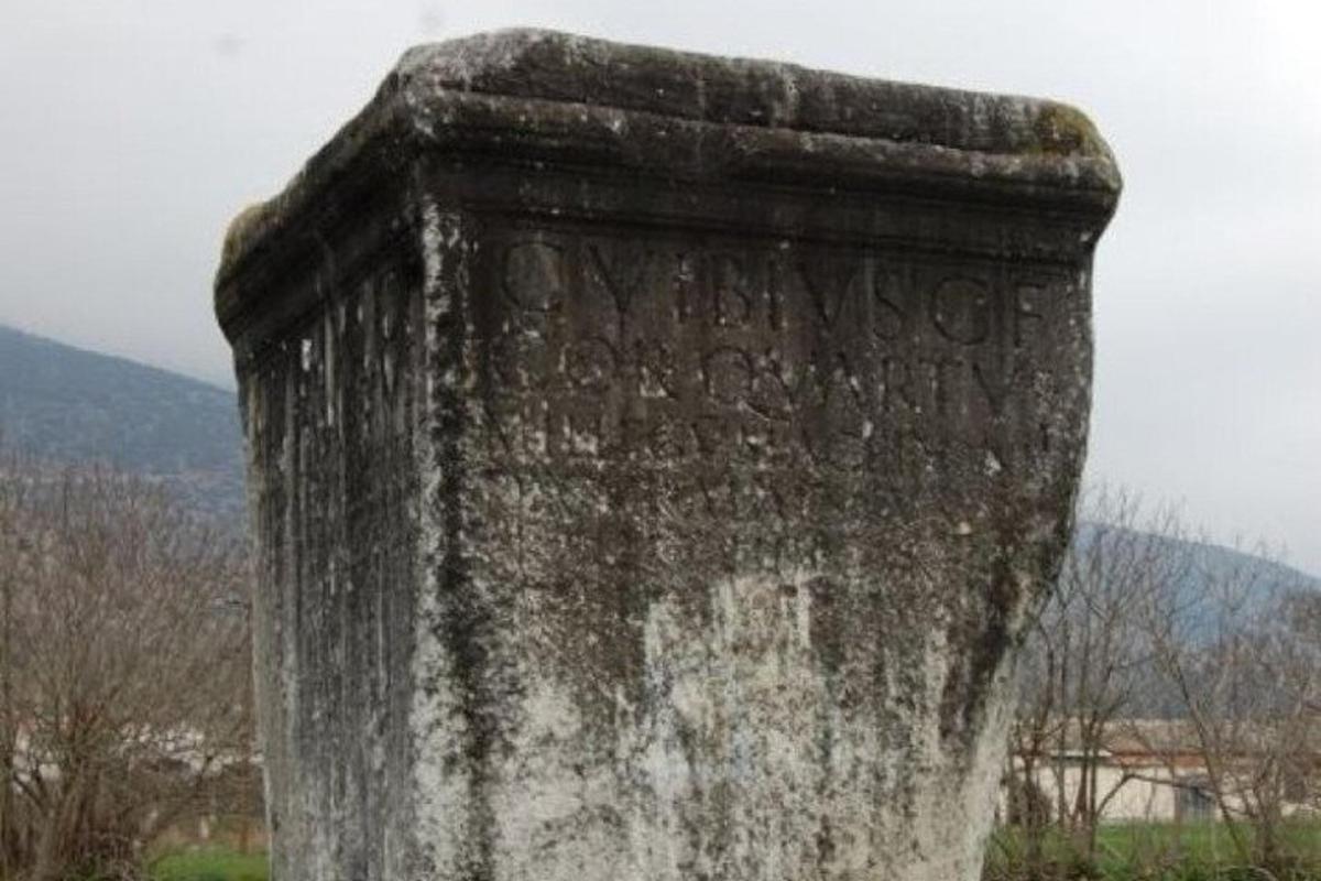 μια πέτρινη κολόνα με επιγραφή σε ένα χωράφι